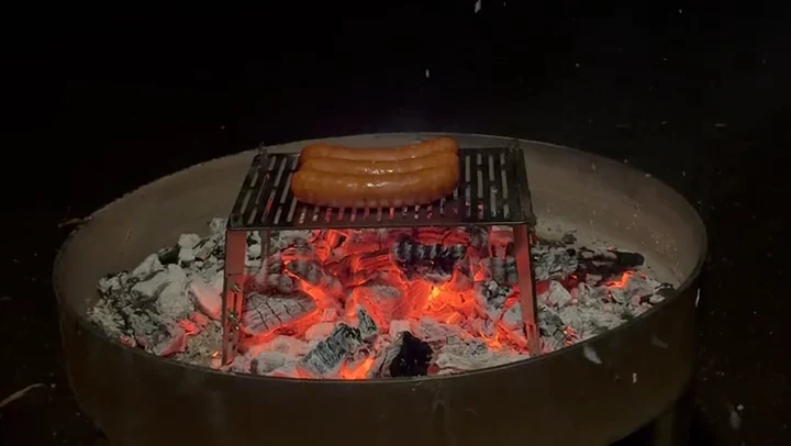 Der Flambini Lagerfeuergriller im Einsatz über glühender Kohle
